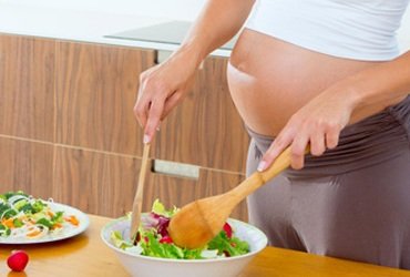 Mujer embarazada preparando una ensalada