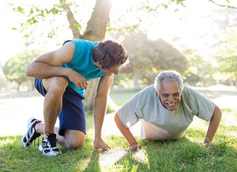Hombre mayor realizando ejercicio junto a personal trainer